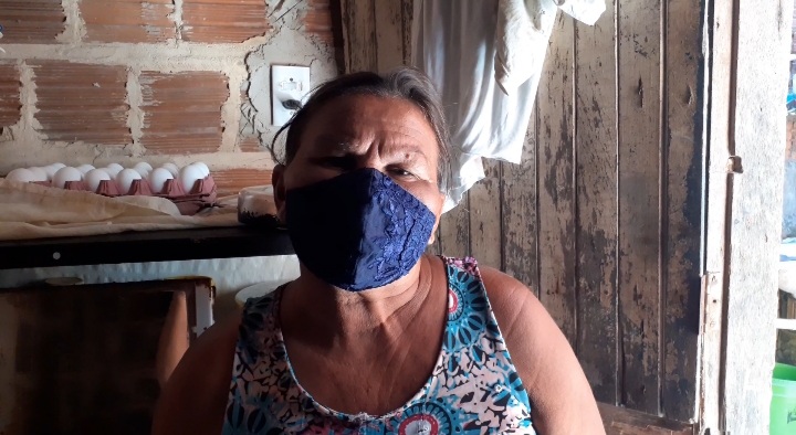 Dona Maria Luzia em sua casa usando máscara 