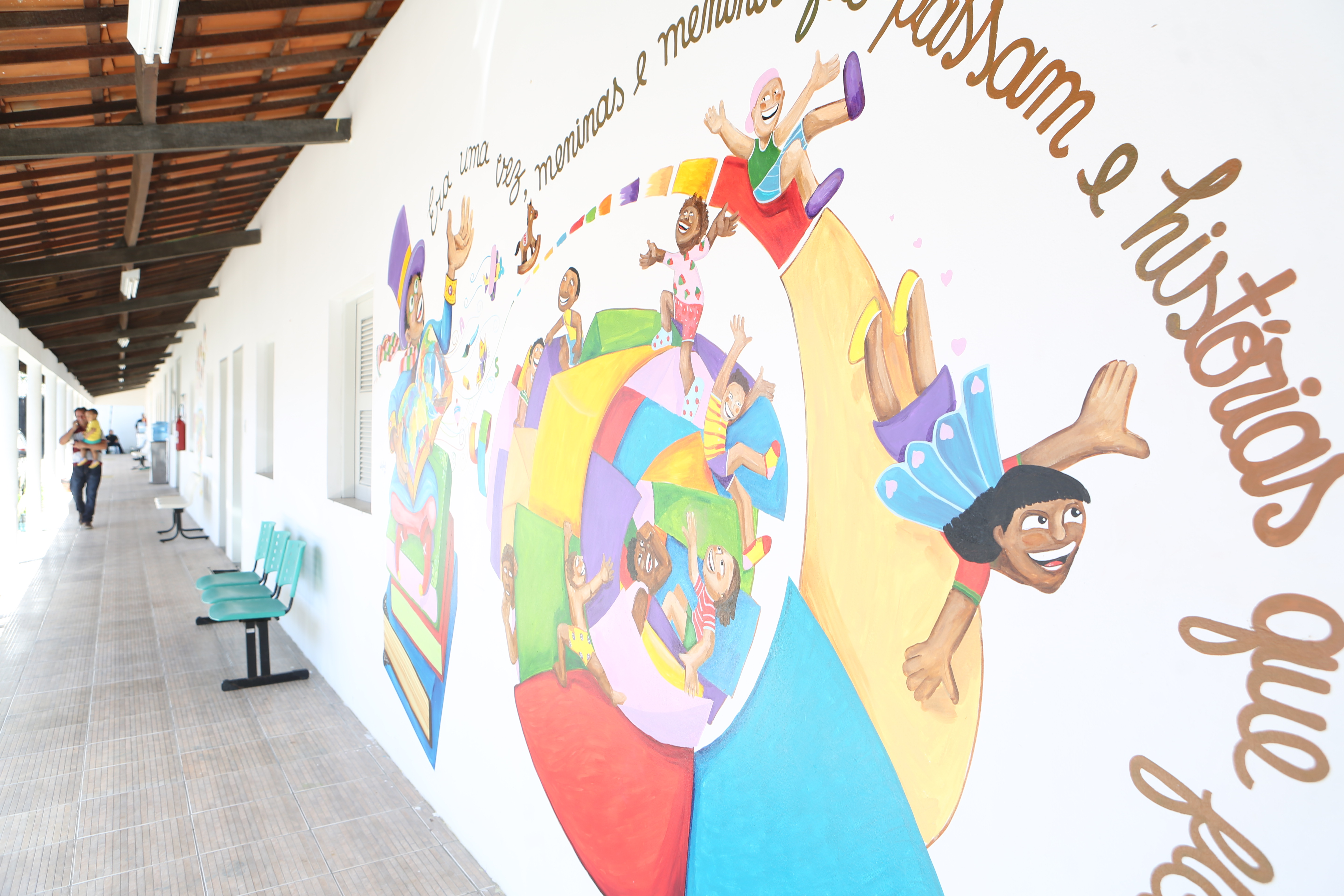 a foto mostra um pátio com um mural colorido pintado em uma das paredes