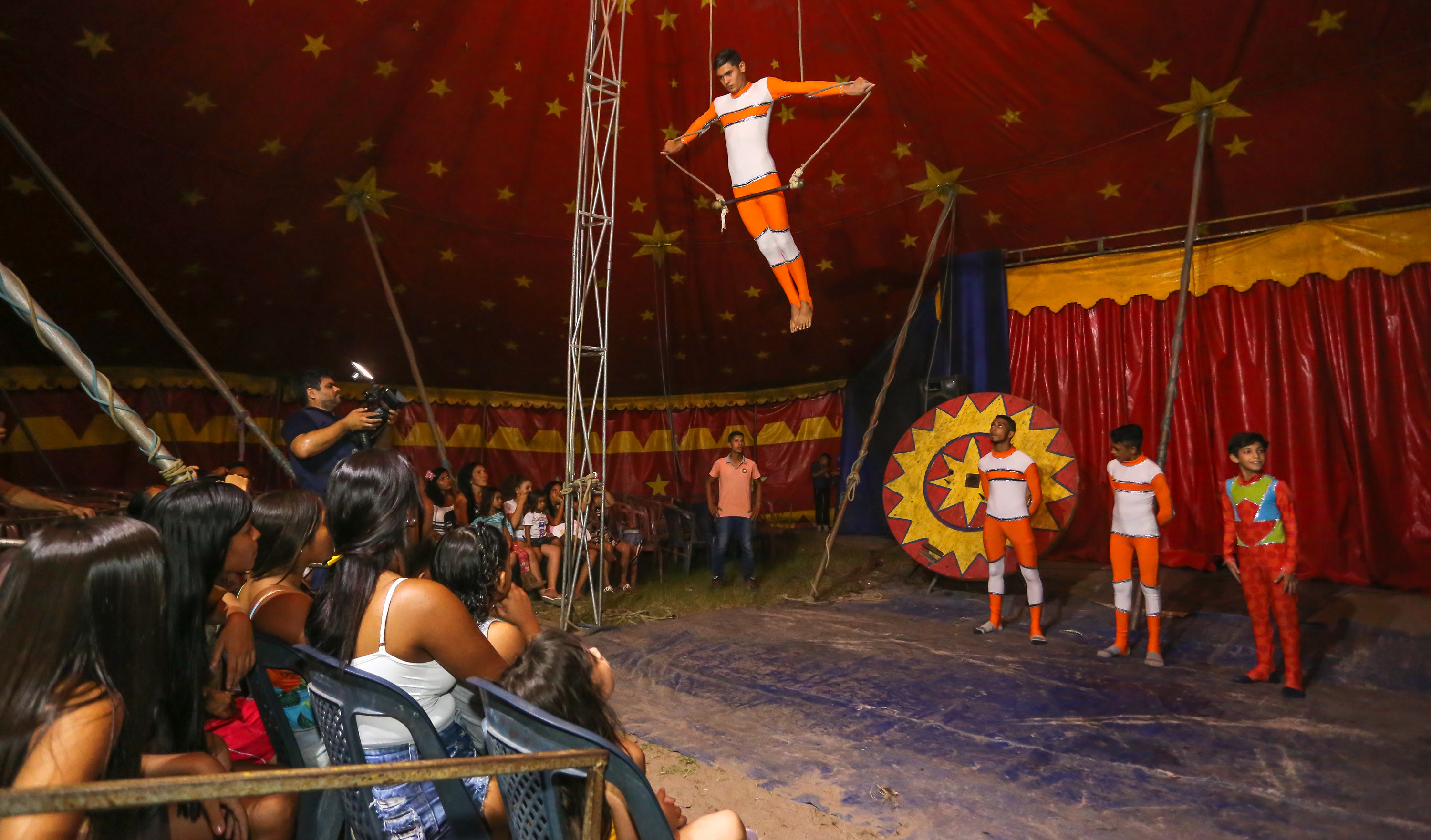 rapaz se apresenta no trapézio de um circo