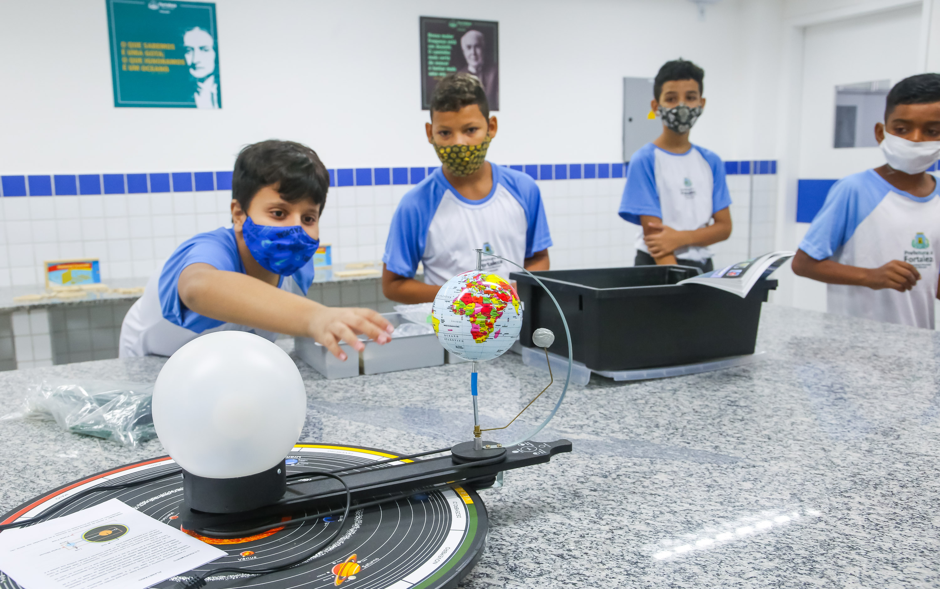 aluno observa equipamento com um globo terrestre, utilizado no laboratório de ciências