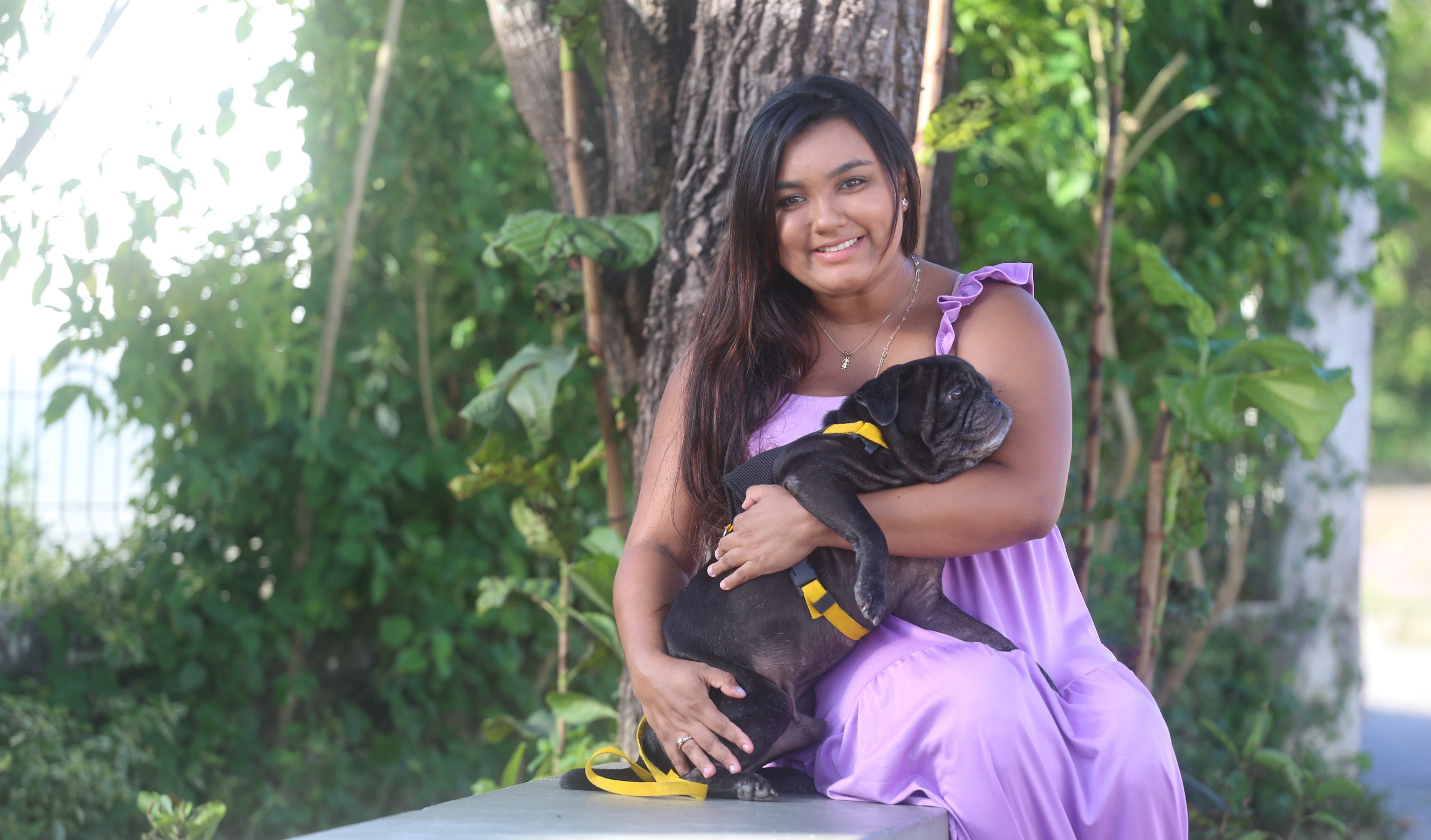 Tutora e cão posam para foto na frente da Clínica Veterinária de Fortaleza - Jacó. 