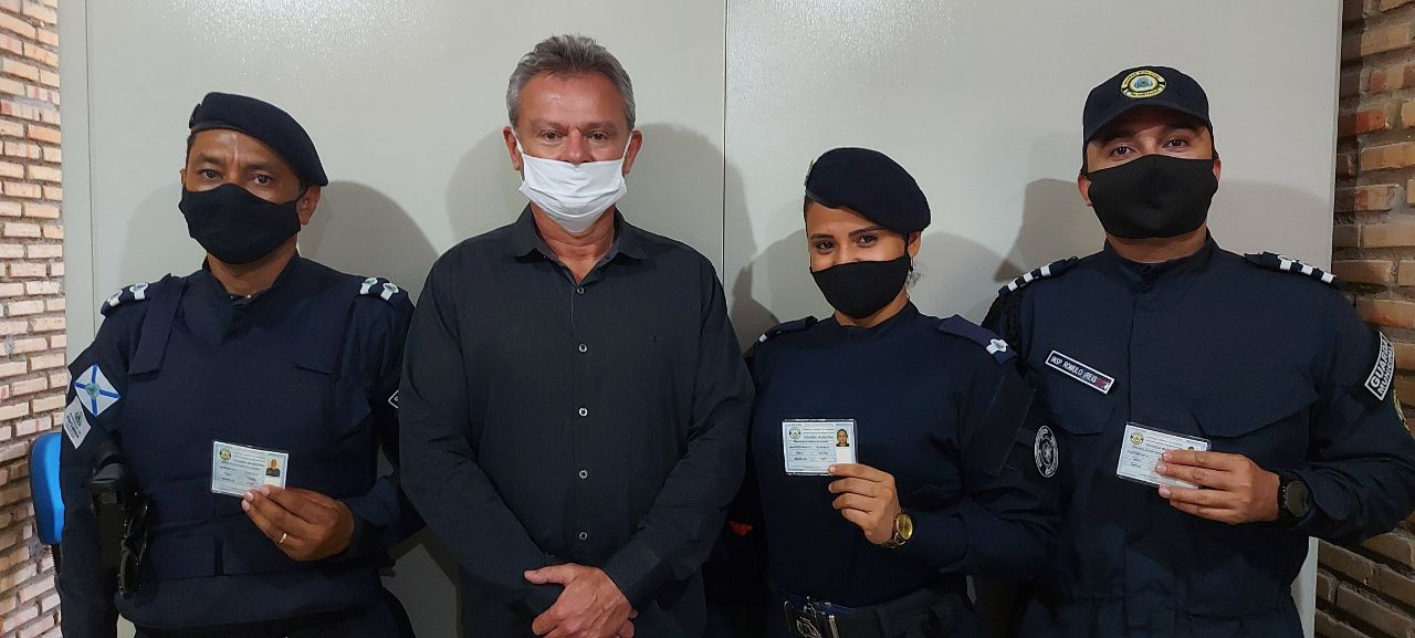 quatro guardas usando máscara e posando para a foto com carteira funcional em mãos
