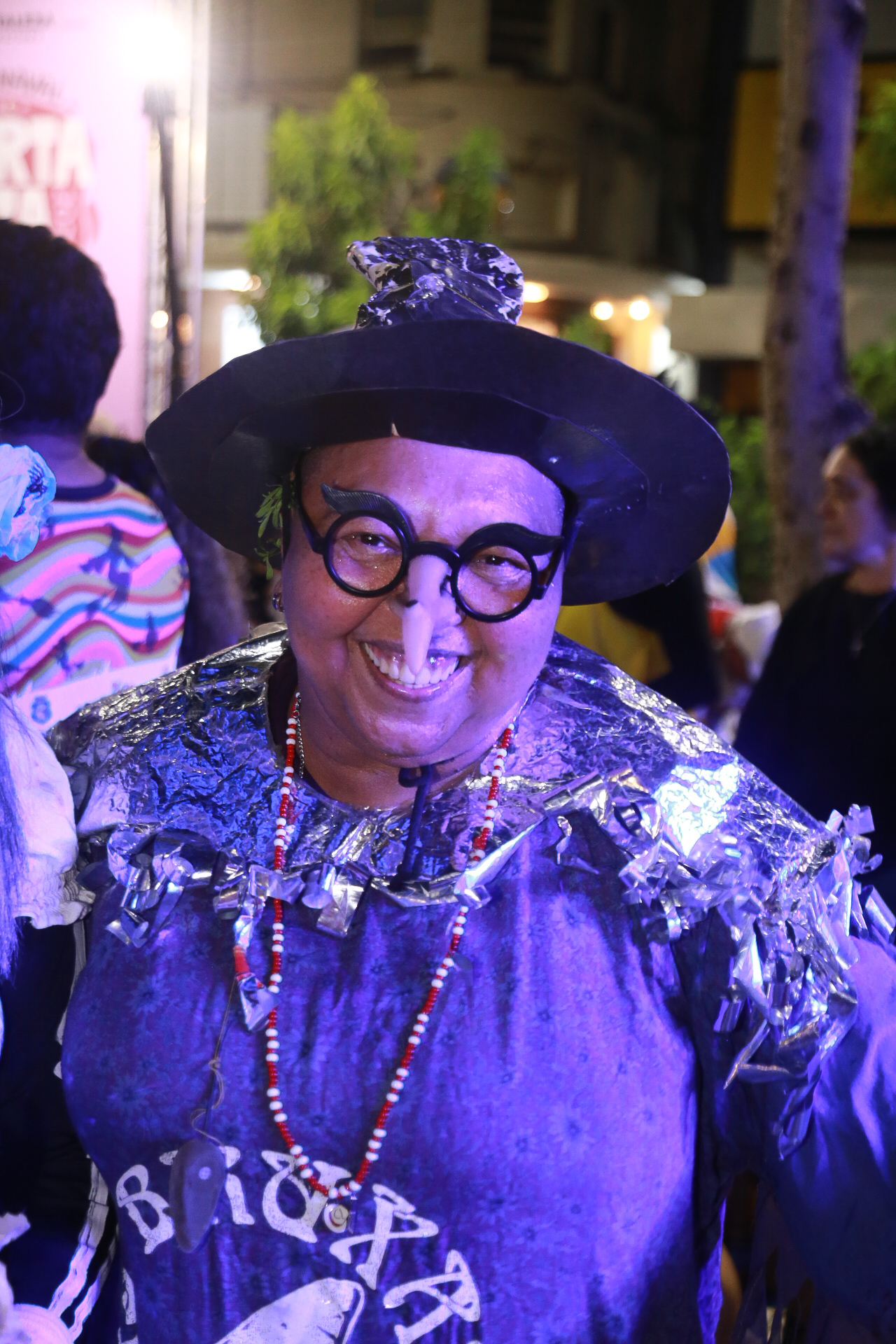 Margarida fantasiada de bruxa, com roupa e chapéu da cor roxa