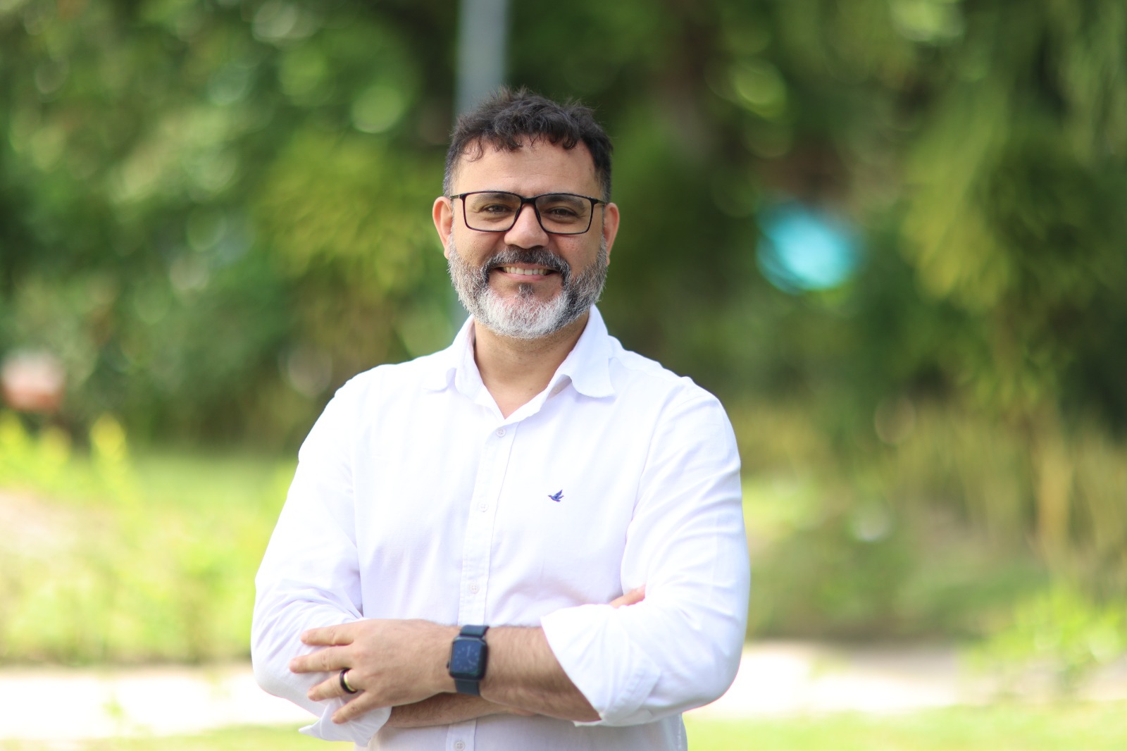 Jovanil posa para a foto de braços cruzados, ele veste uma camisa branca