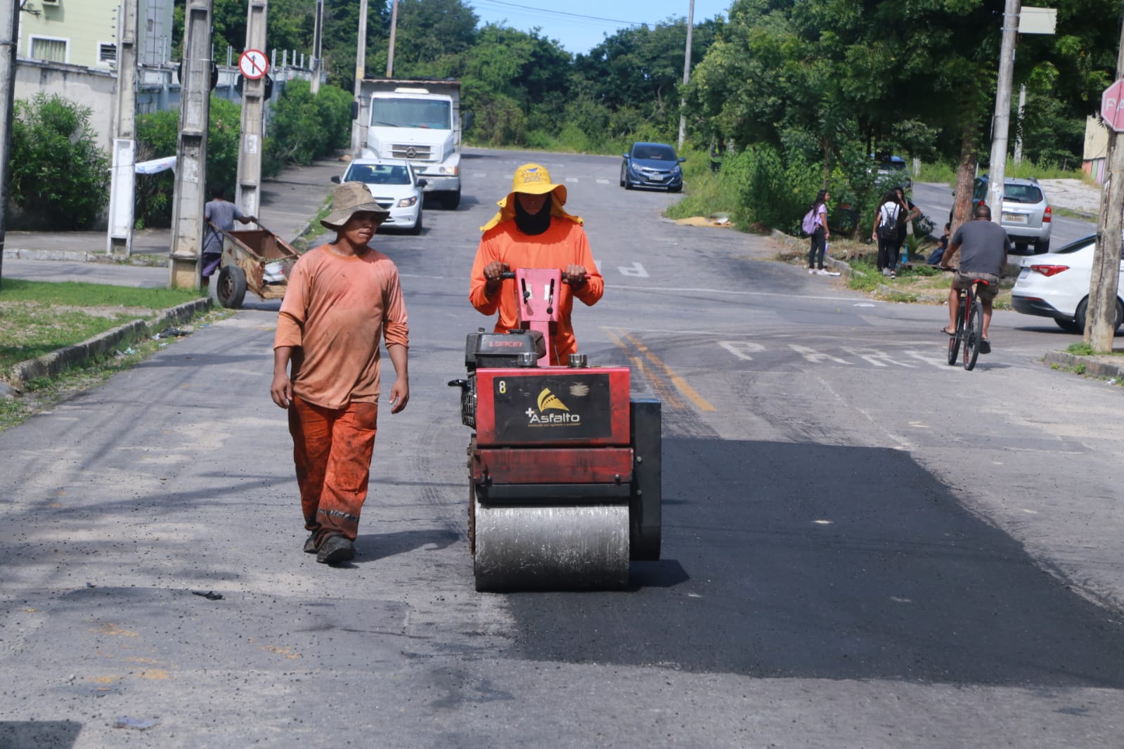 homens trabalhando em recapeamento de asfalto com máquina