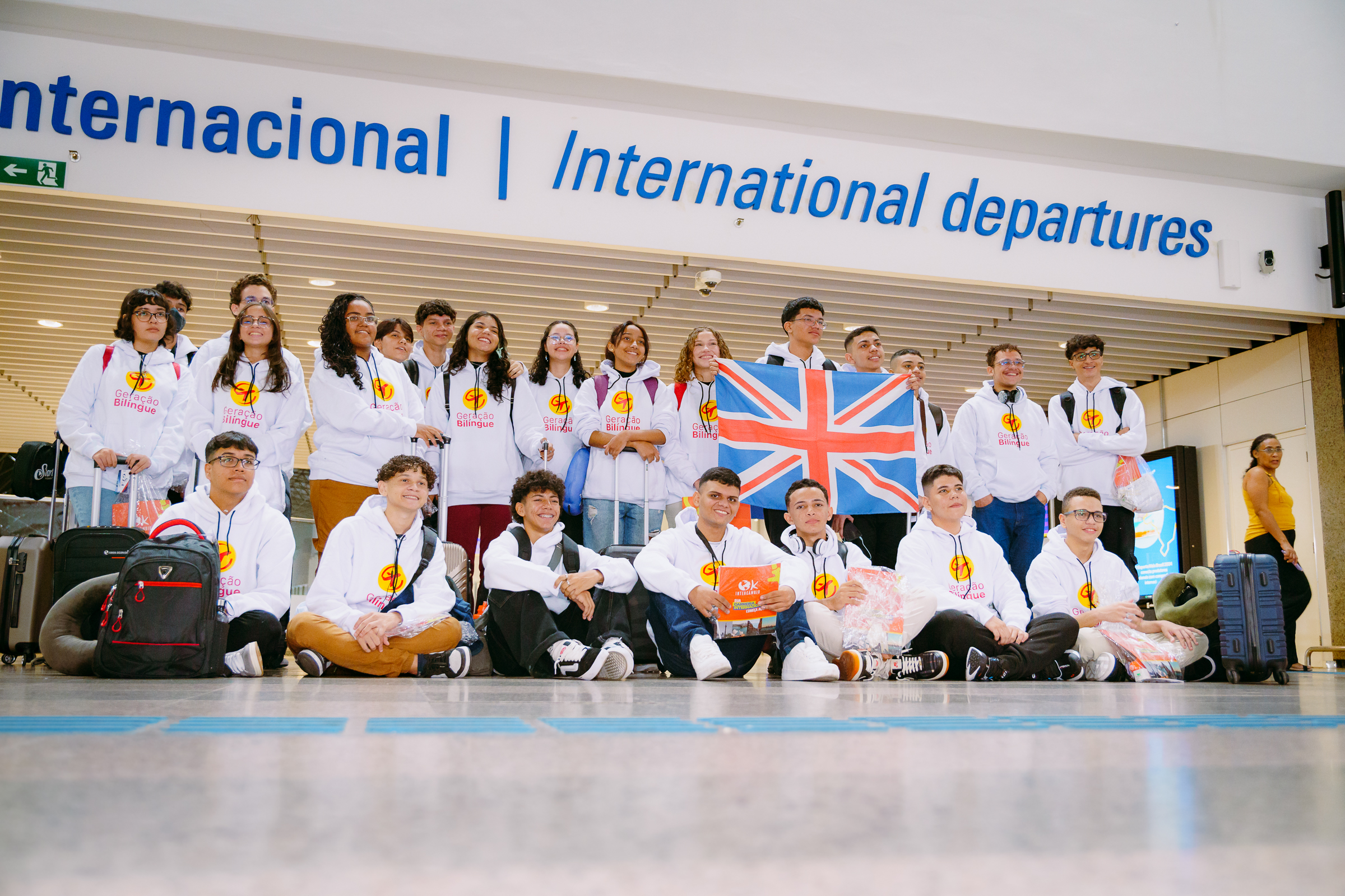 Grupo de jovens sorrindo em ala de embarque internacional do Aeroporto de Fortaleza.