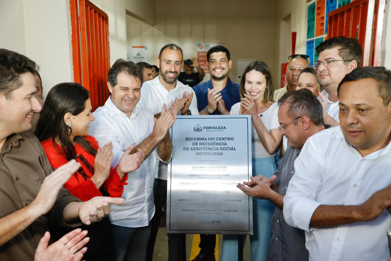 O prefeito Evandro Leitão, a vice Gabriella Aguiar e uma grande quantidade de pessoas estão em volta da placa do Cras Messejana recém descerrada