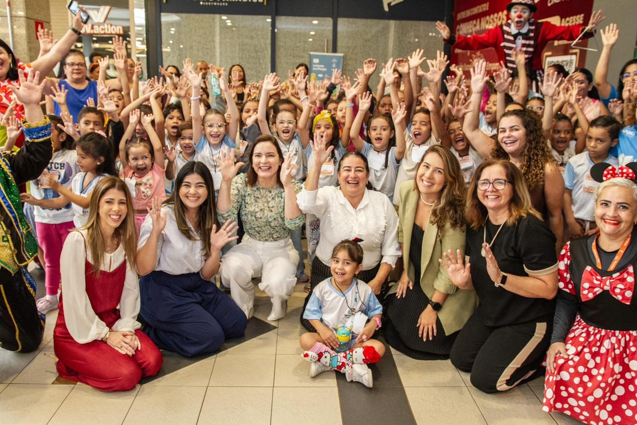Diversas pessoas posam para a foto rindo e levantando os braços