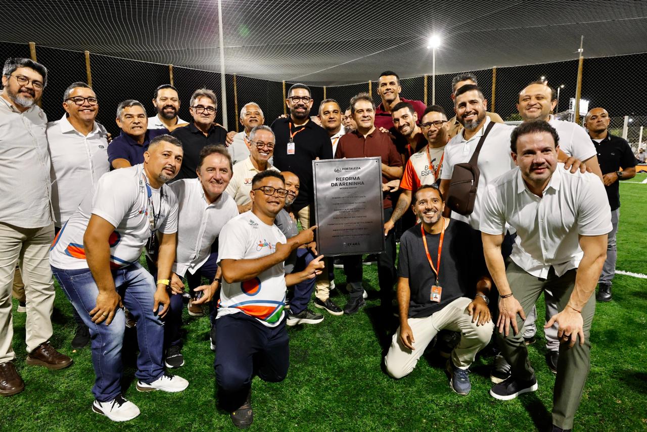 A foto mostra o prefeito Evandro Leitão, gestores, vereadores e pessoas da comunidade que participaram do evento. O prefeito está segurando a placa da areninha.