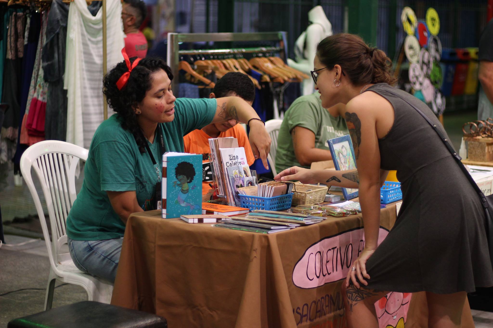 Expositor na Feira Mercado Coletivo apresentado material para frequentadora