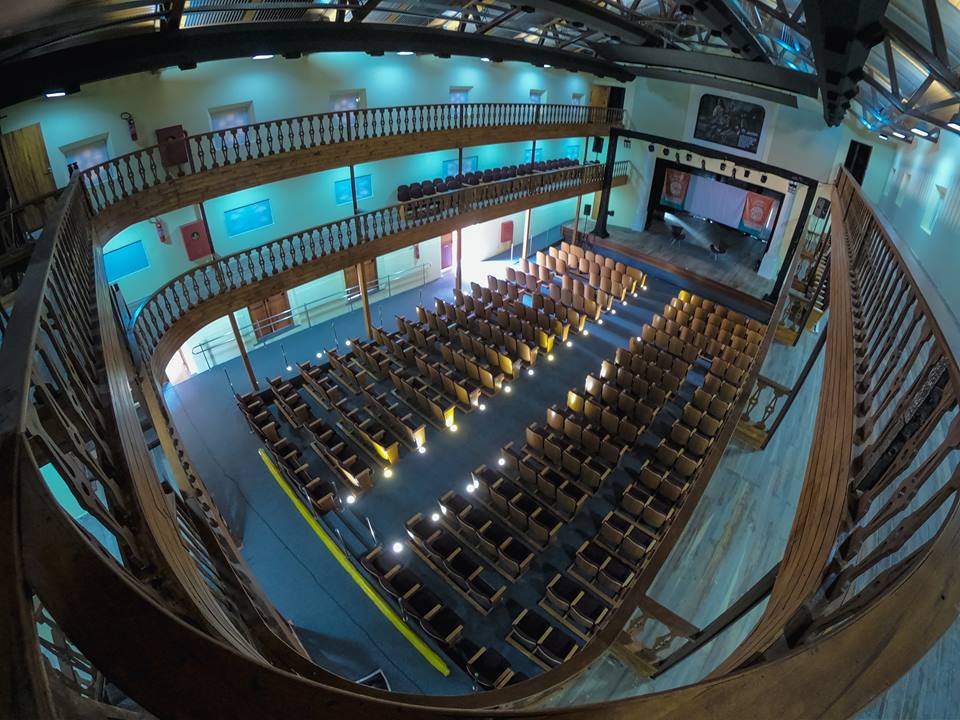 Imagem geral do espaço interno do teatro, tirado do segundo pavimento, mostras as poltronas e palco.